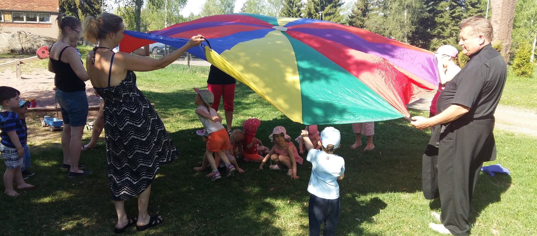 Perhekerholaiset leikkivarjon äärellä toukokuussa 2018.