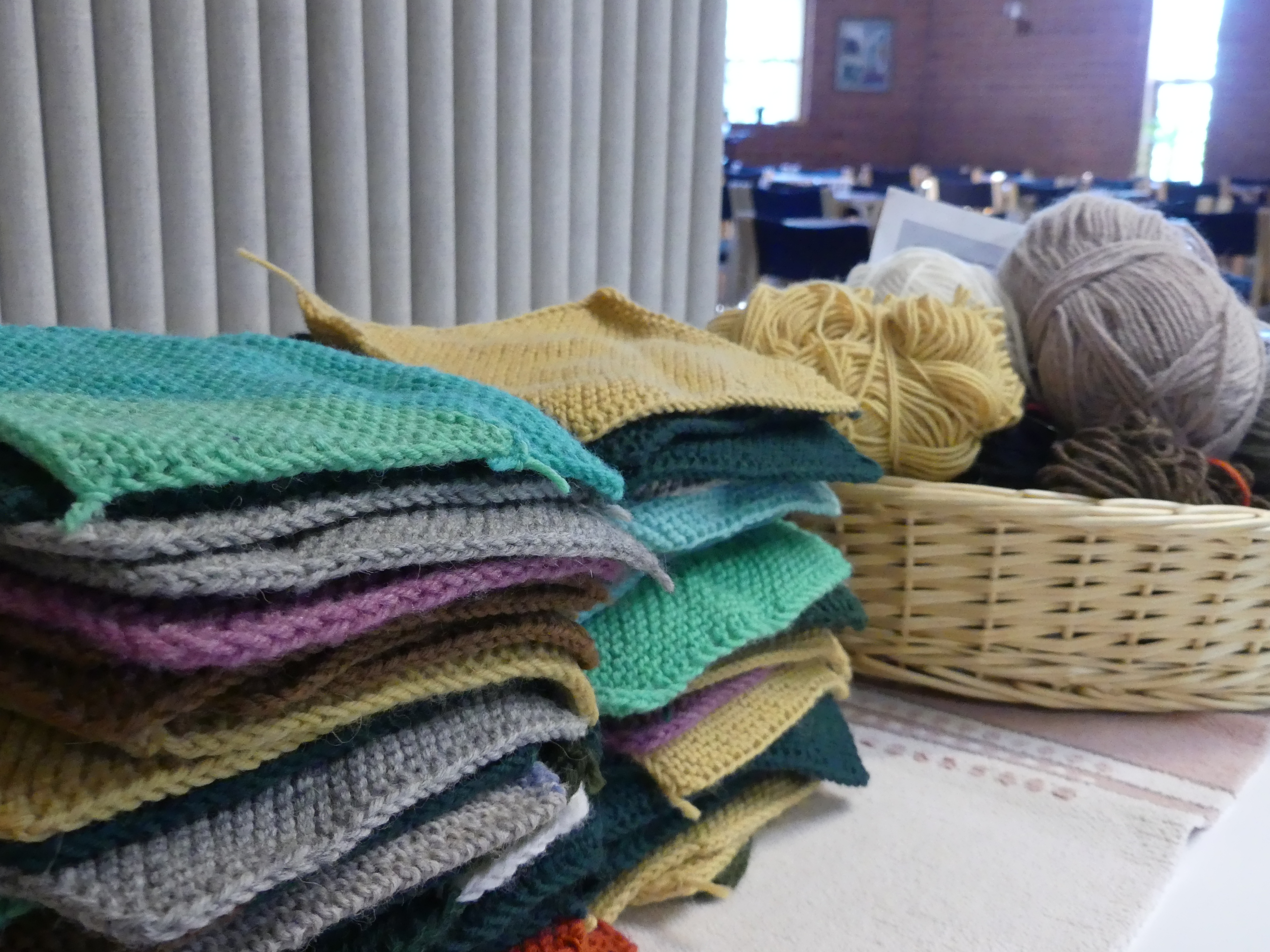 Erivärisiä neuletilkkuja ja lankakeriä Vinkkilän seurakuntatalon salin pöydällä.