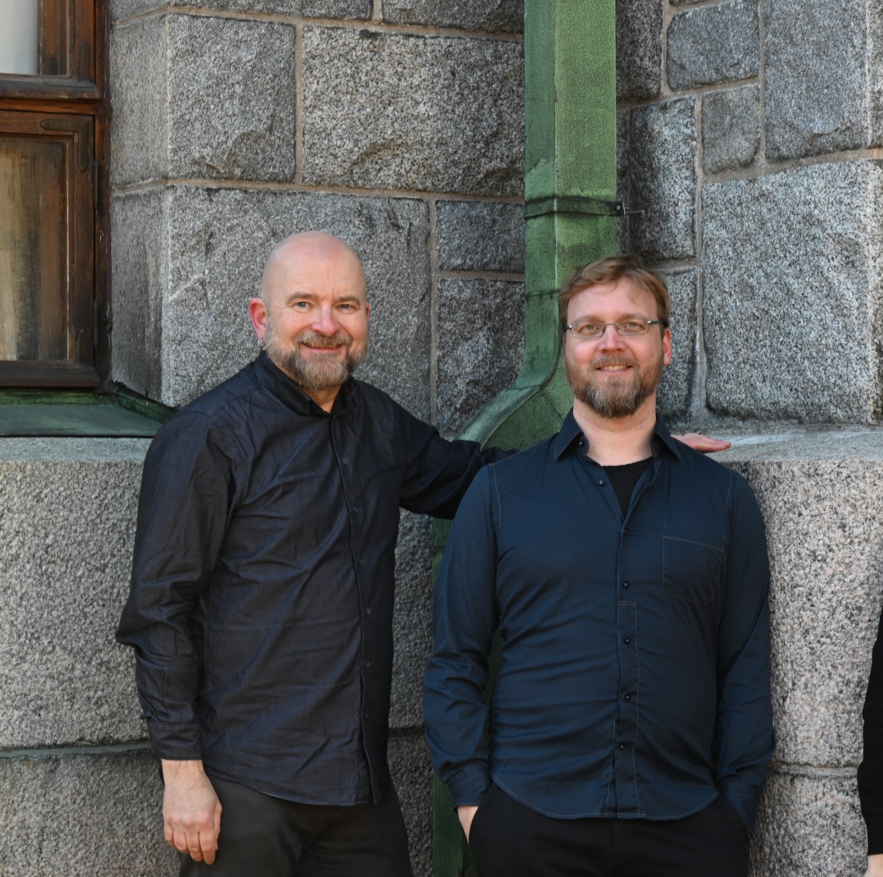 Valokuvassa Pekka Silén ja Olli Hyyrynen seisovat hymyillen, taustalla graniittiseinä.