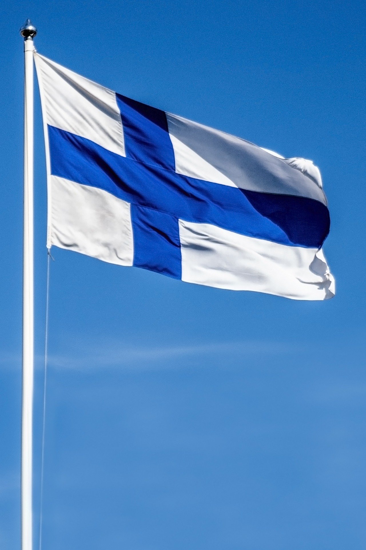 Suomen lippu liehuu sinistä taivasta vasten
