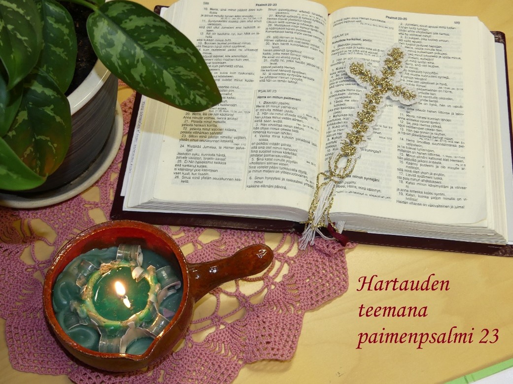 Viikkohartaus: Hyvän paimenen psalmi Pöydällä avoin raamattu, jossa esillä psalmi 23, risti, viherkasvi sekä palava kynttilä. Teksti: Hartauden teemana paimenpsalmi.