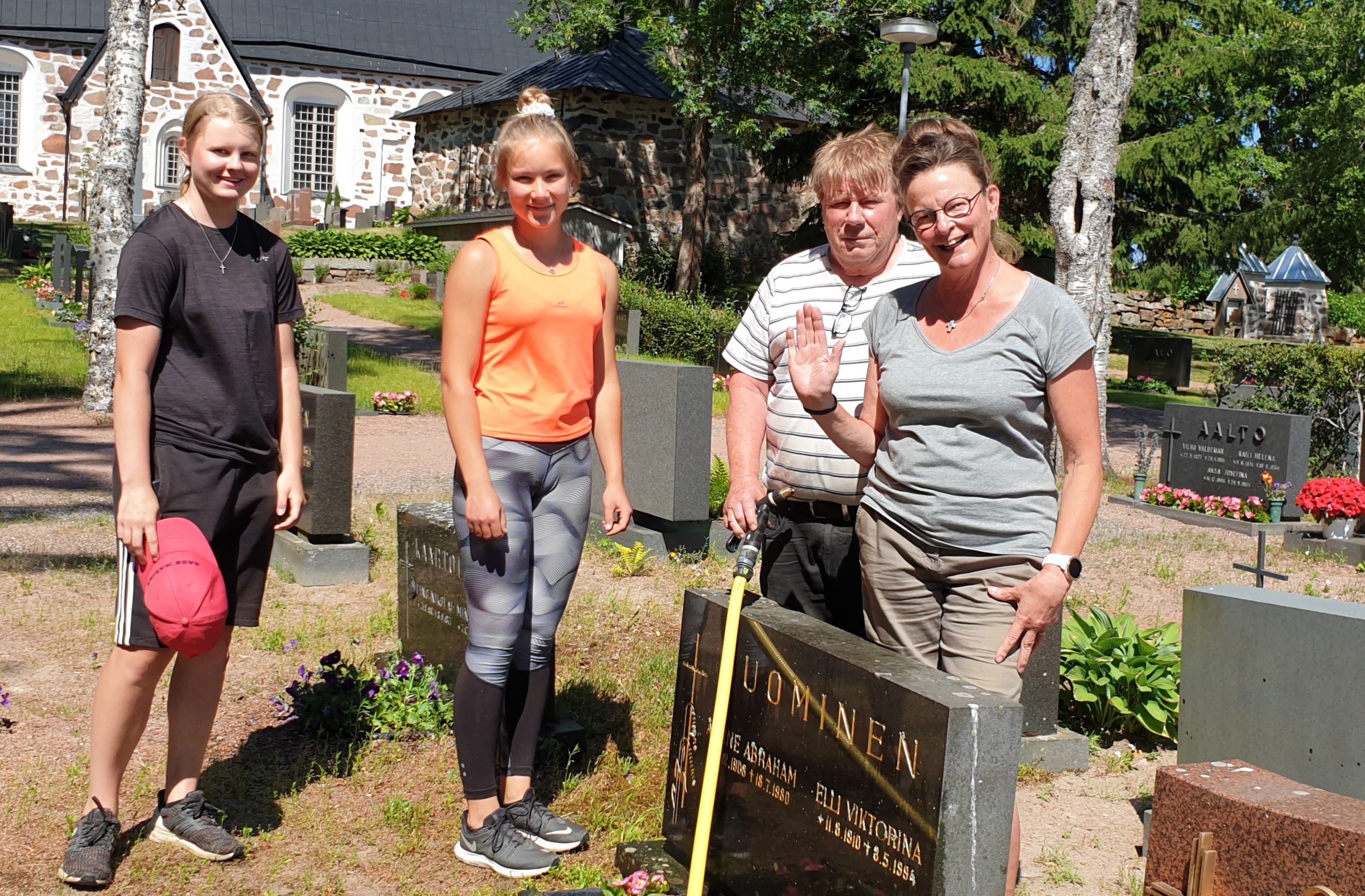 Työntekijät rivissä, taustalla Vehmaan keskiaikainen kivikirkko ja vehreä hautausmaa